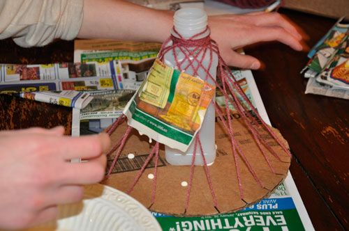 two people are making something out of paper and twine on a table with magazines