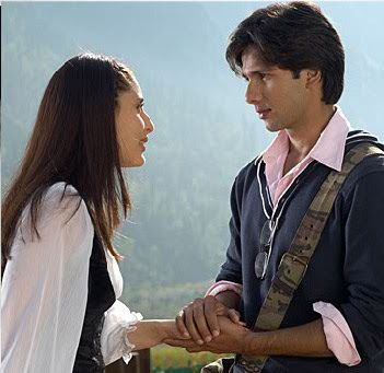 a man and woman standing next to each other on top of a hill talking together