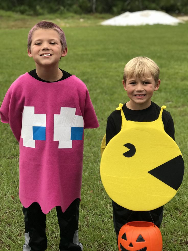 two young boys dressed up as pacman and chickbob with pumpkins on the grass