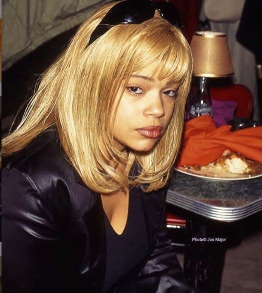 a woman with blonde hair sitting in front of a plate of food on a table