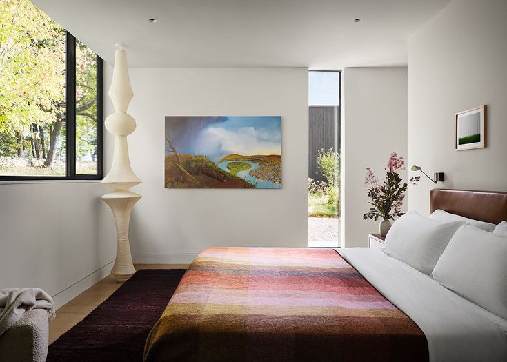 a bedroom with a large bed next to a painting on the wall and an open window