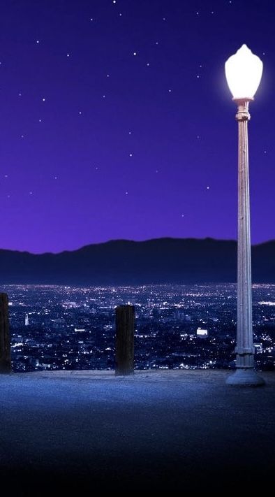 a street light sitting on top of a tall pole next to a night sky filled with stars