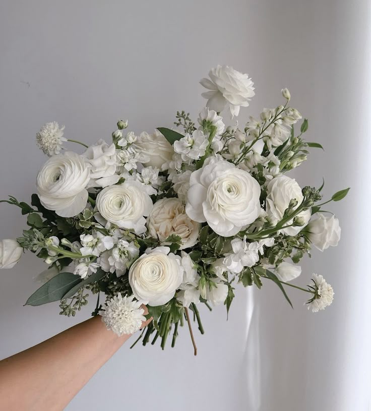 a hand holding a bouquet of white flowers