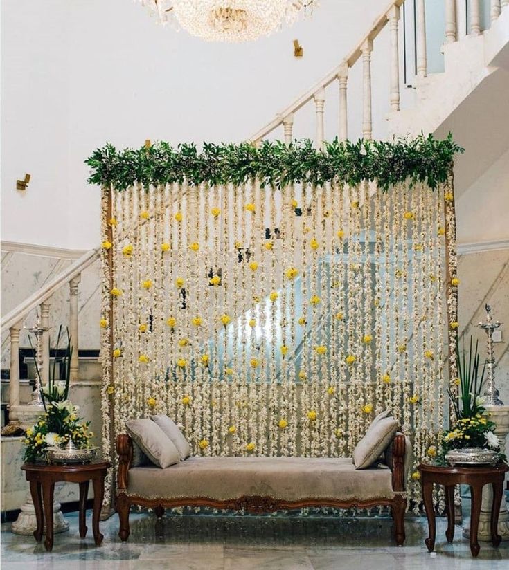 a living room filled with furniture under a chandelier covered in yellow flowers and greenery