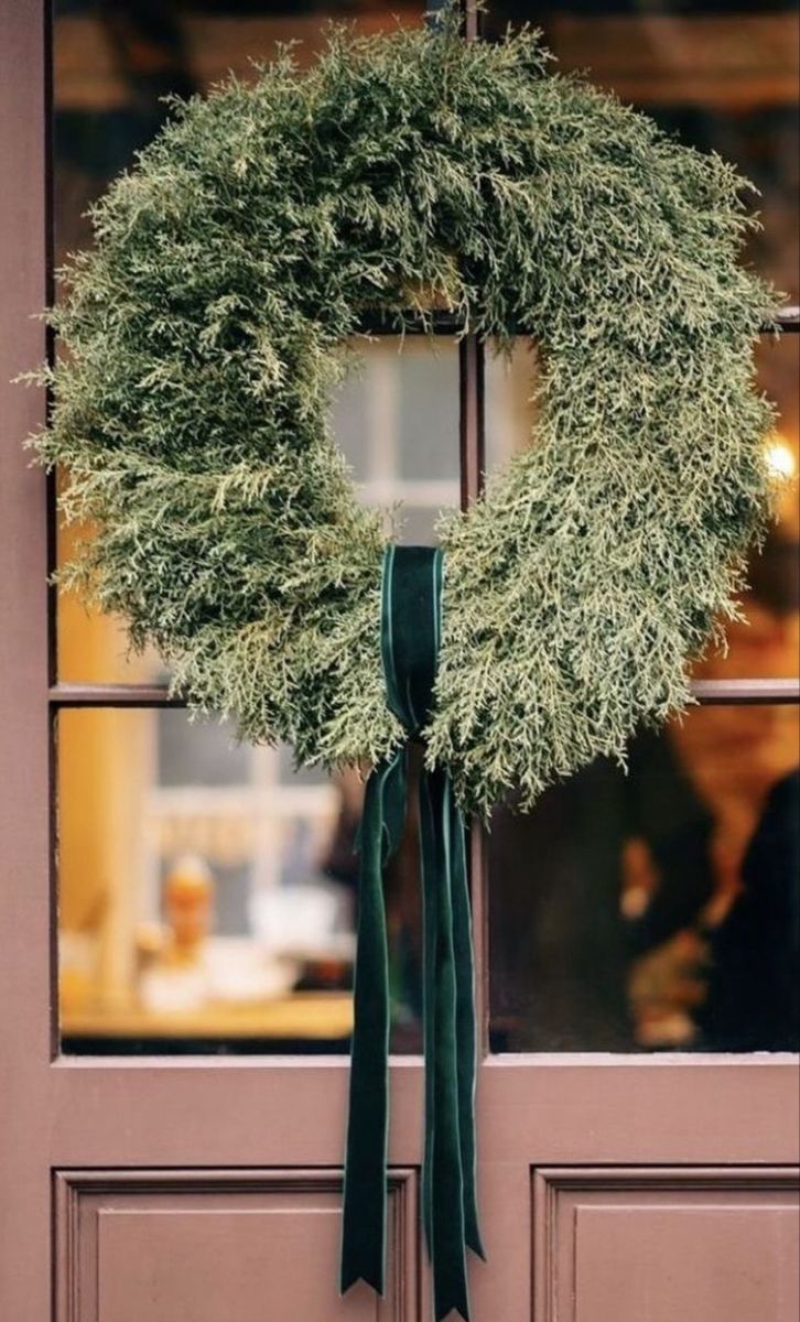 a wreath hanging on the front door of a building with a green ribbon tied around it