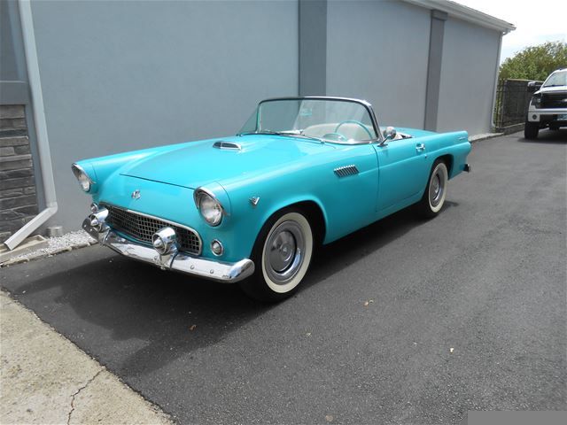 an old blue car parked in front of a building