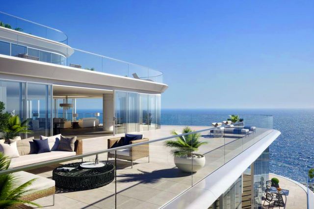 a balcony overlooking the ocean with couches and tables