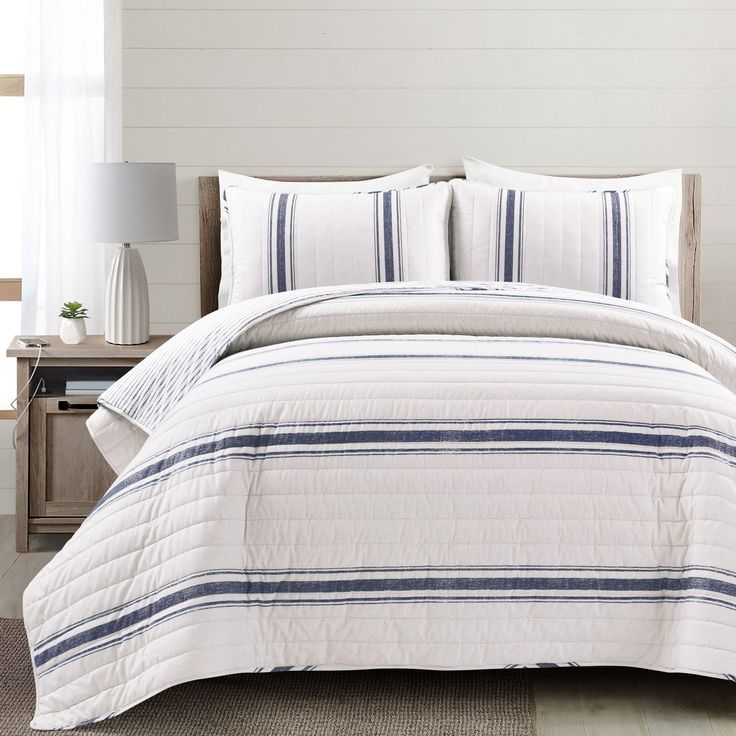 a bed with white and blue striped comforters