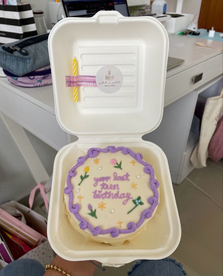 a decorated birthday cake in a foam container with the lid open to show it's inside