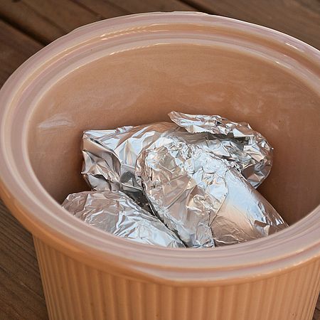 a brown container filled with foil sitting on top of a wooden table