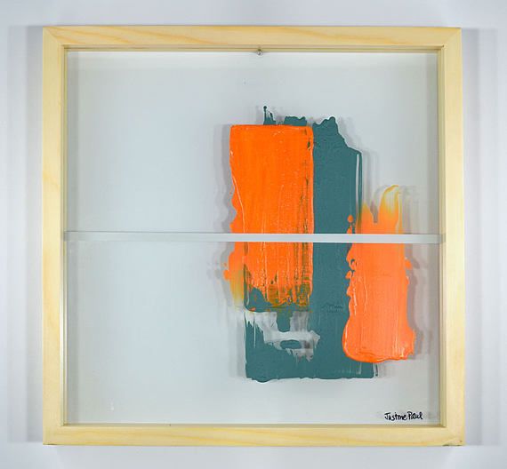 an orange and green piece of art in a wooden frame on a white wall,