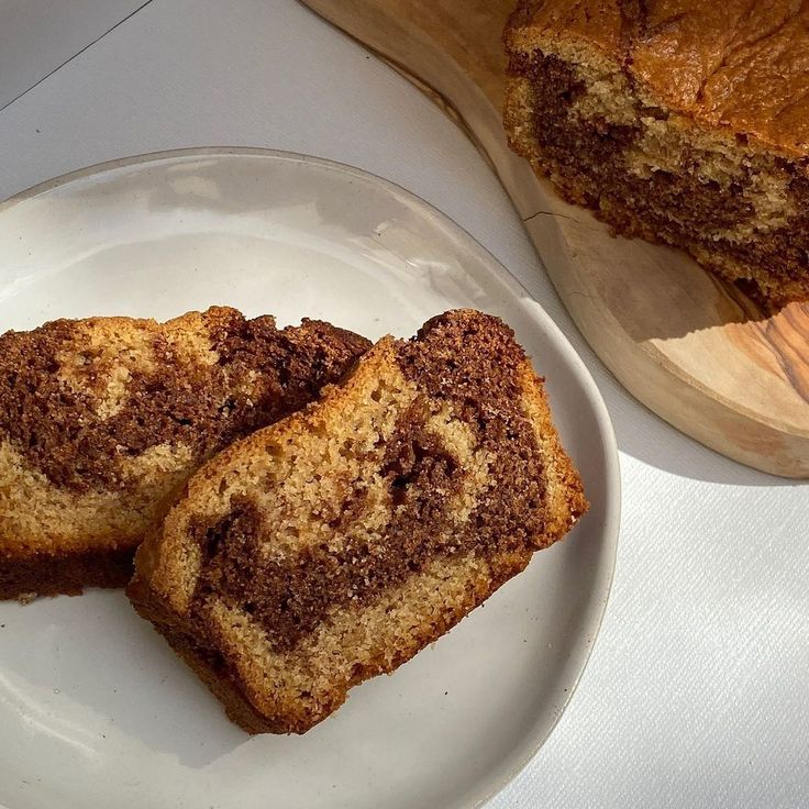 two slices of cinnamon swirl bread on a plate next to a loaf of banana bread