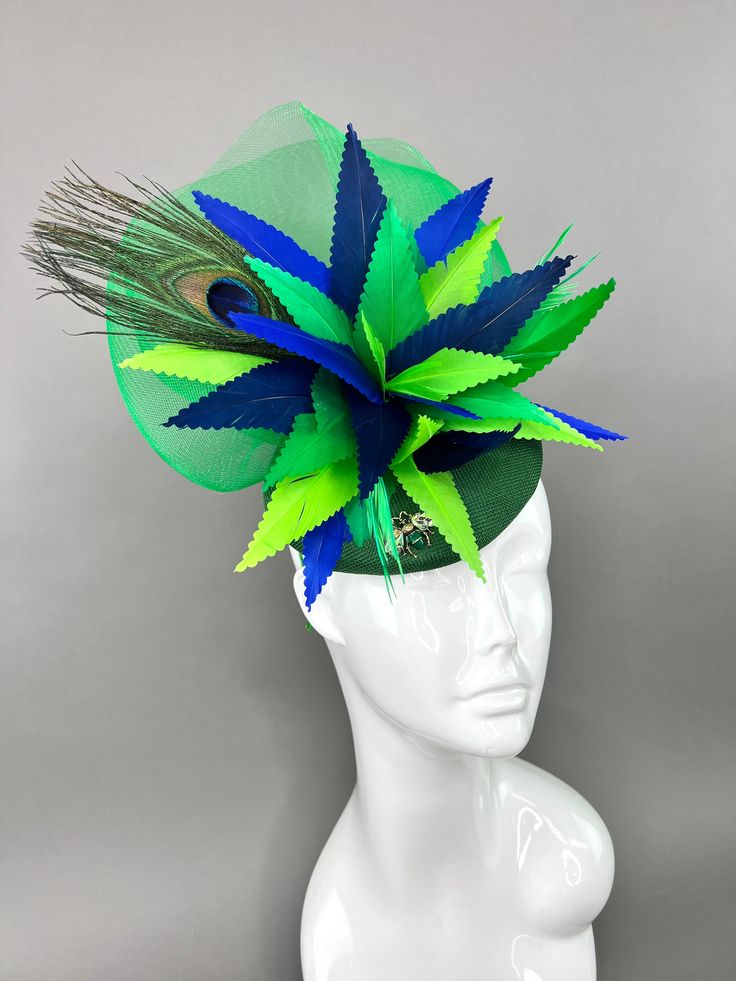 Emerald green, linen fascinator adorned with shades of navy and royal blue, lime and emerald green feathers. Attaches with interchangeable headband or hair clip option. Can be worn on the left or right side. Light and comfortable to wear. Prior to purchase, please note that all sales are final. Don't forget to check us out on Instagram @TheHatHive. Green Spring Headband, Green Headband For Spring, Green Mini Hat Headband For Kentucky Derby, Green Headband Mini Hat For Kentucky Derby, Adjustable Green Headband Fascinator, Green Headband Fascinator For Royal Ascot, Summer Green Feathered Headpiece, Green Feathered Mini Hat For Kentucky Derby, Adjustable Green Headpiece For Royal Ascot