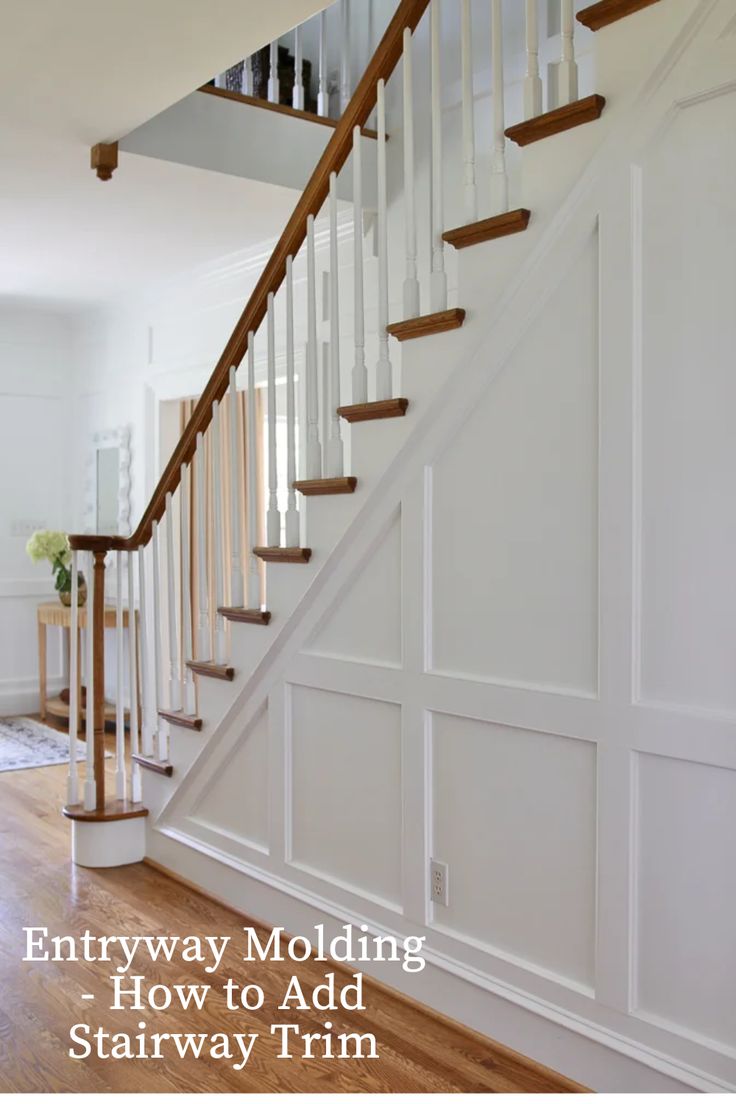 a white staircase with wooden handrails and wood flooring in a home's entryway