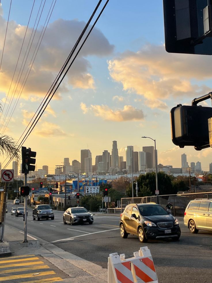 cars driving down the road in front of a city skyline