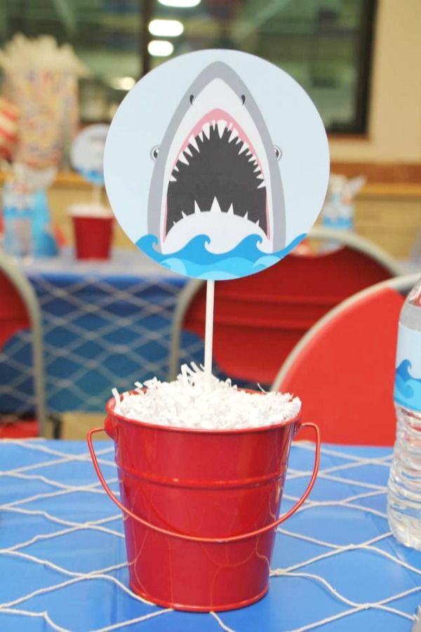 a red bucket filled with white rice sitting on top of a blue table covered in shark decorations