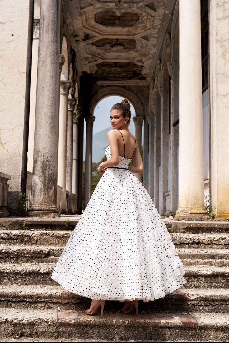 a woman in a white dress standing on steps with her back turned to the camera