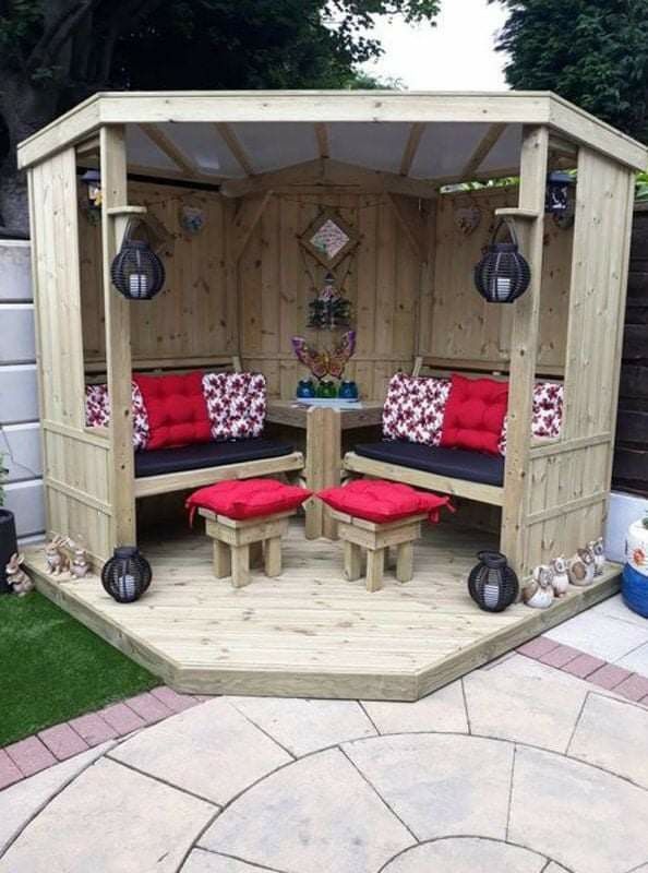 a wooden gazebo with red cushions on it's sides and two benches in the middle