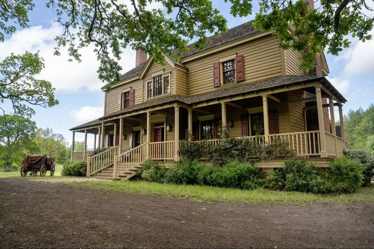 a large brown house sitting on top of a lush green field