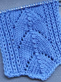 a blue knitted dishcloth hanging from a hook on a gray cloth with white stitchs