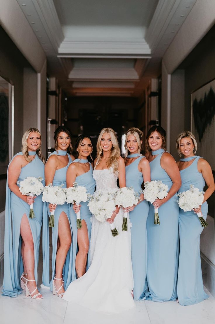 a group of women standing next to each other holding bouquets and posing for the camera