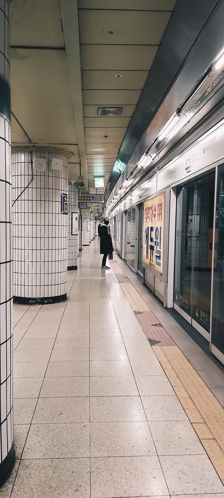 an empty subway station with people walking on the platform