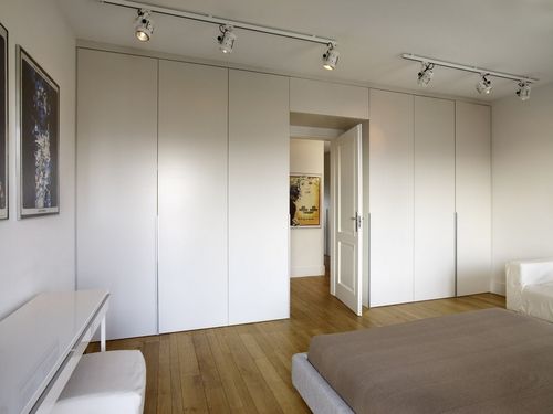 a bedroom with white walls and wooden flooring is pictured in this image, there are lights on either side of the bed