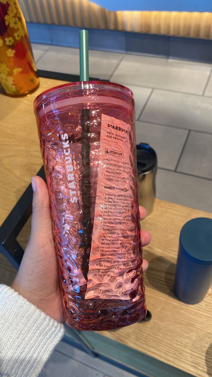 a person holding up a pink tumbler cup