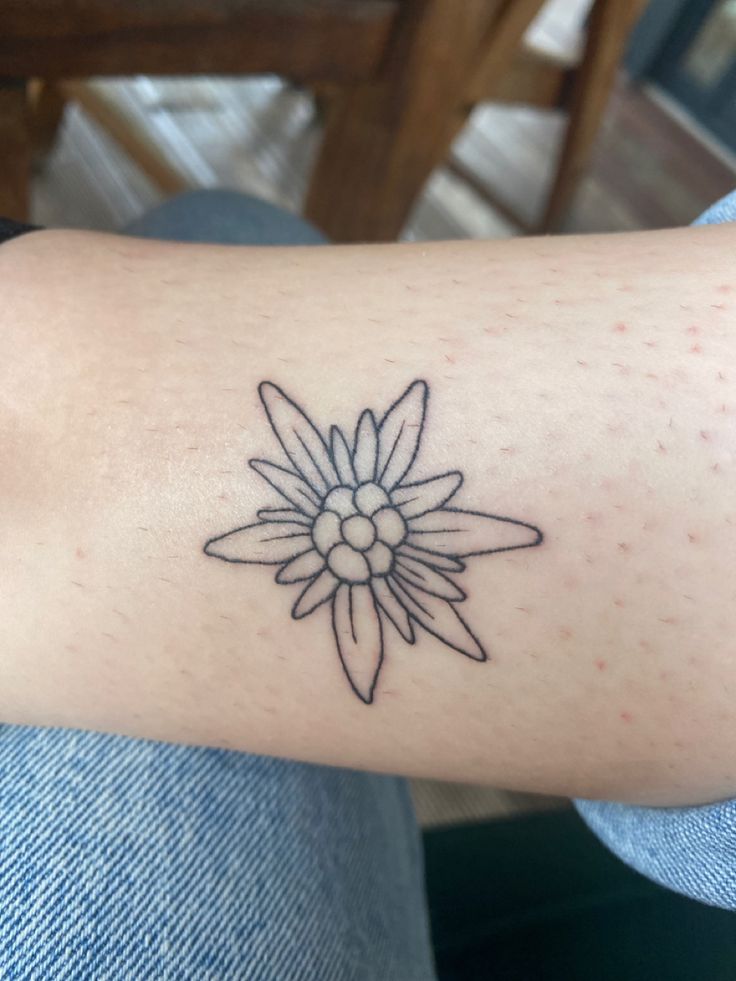 a person with a tattoo on their arm that has a flower in the middle of it