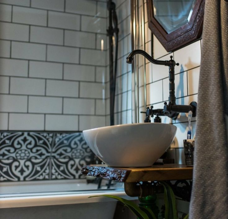 a white bowl sink sitting on top of a wooden shelf next to a bath tub