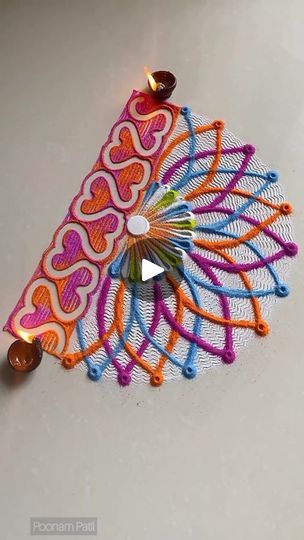 a colorful piece of art made out of string and beads on a white table top