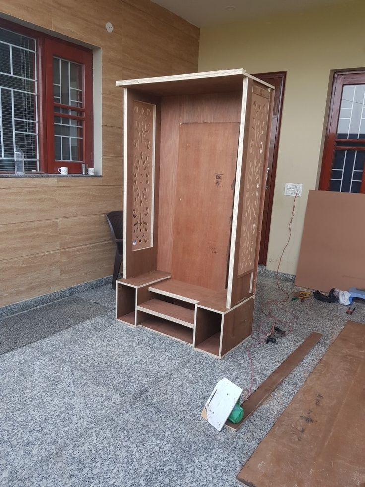 an empty wooden closet sitting in the middle of a room next to boxes and other items