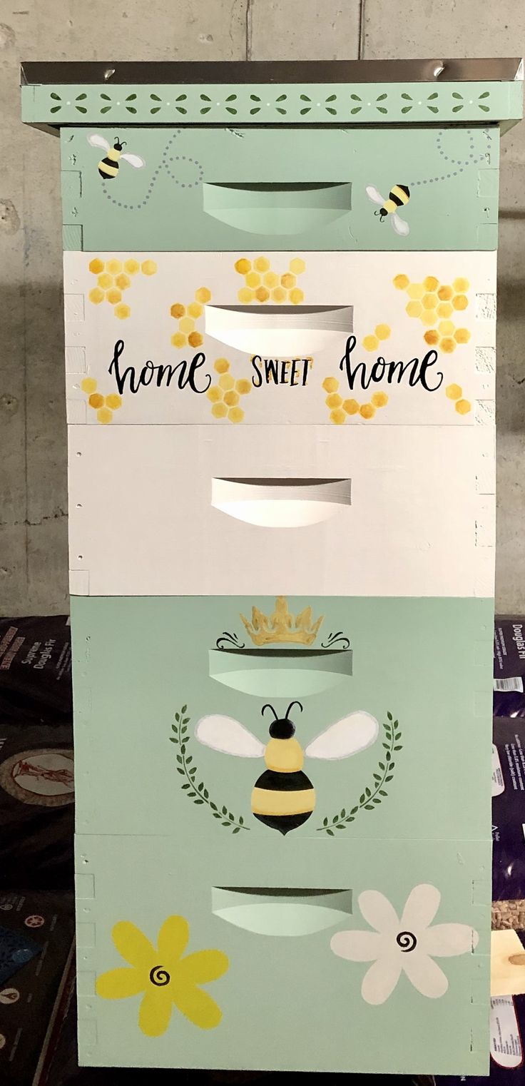 the boxes are stacked on top of each other with bees and flowers painted on them