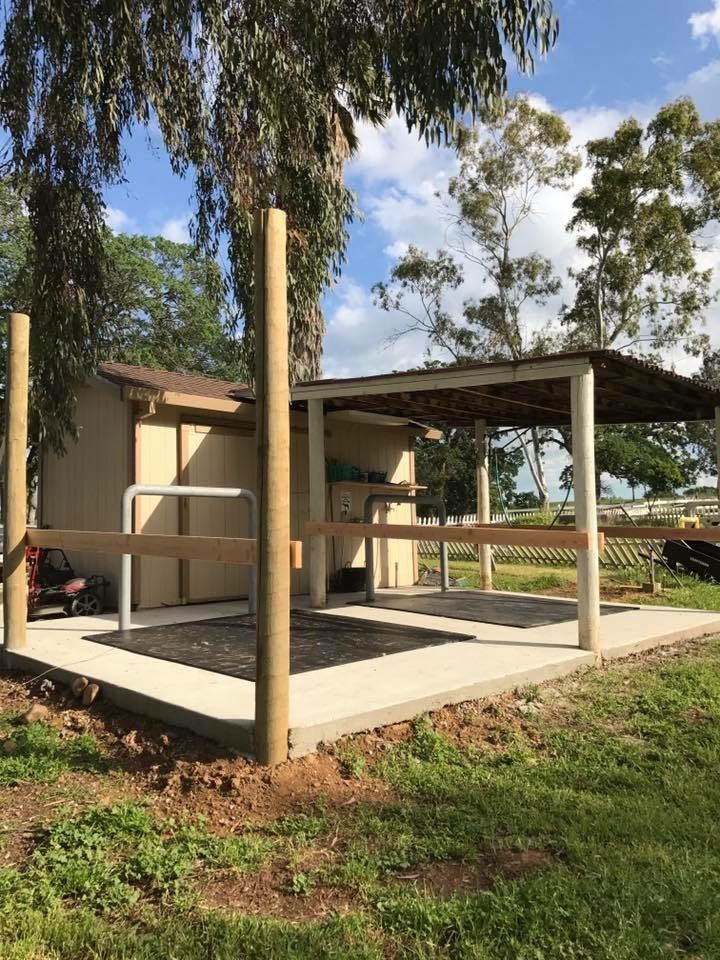 a wooden structure with metal railings in front of a tree and grassy area next to it