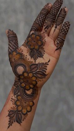 a woman's hand with henna tattoos on it and pine cones in the middle