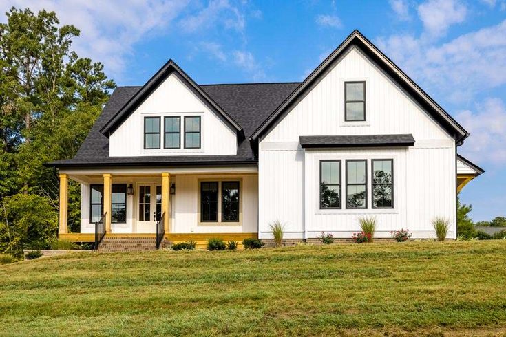 a large white house with black roof and yellow trim on the front porch is shown