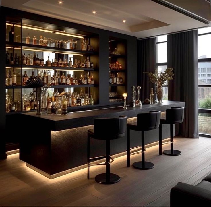 a bar with several stools and bottles on the shelves in front of it at night