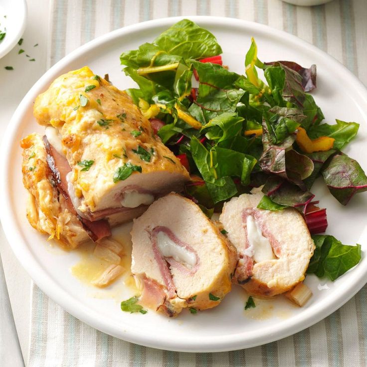 a white plate topped with meat and veggies next to a bowl of salad