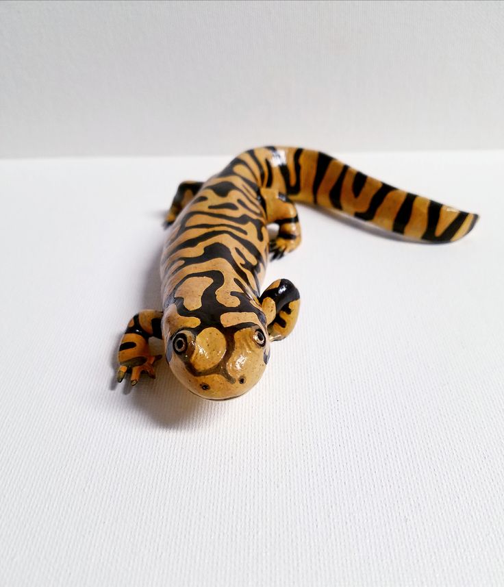 a toy tiger lizard sitting on top of a white surface