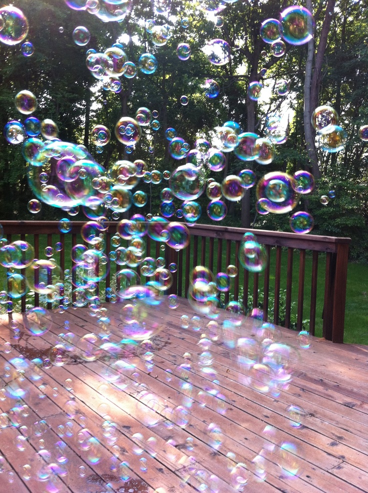 soap bubbles floating in the air over a wooden deck