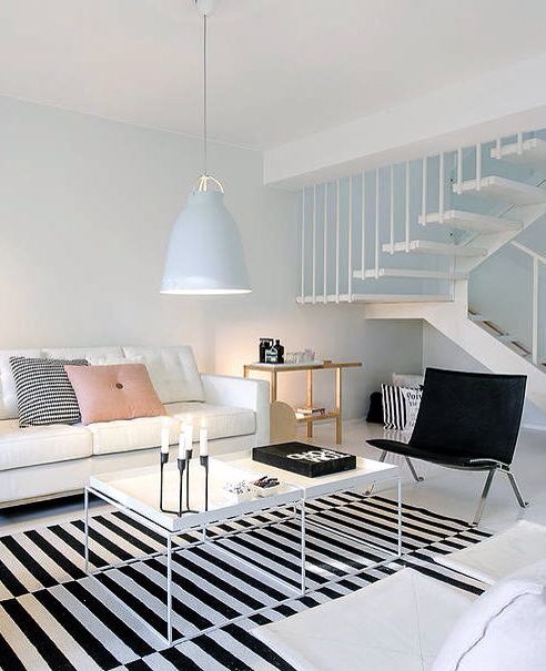 a white living room with black and white rugs on the floor next to stairs