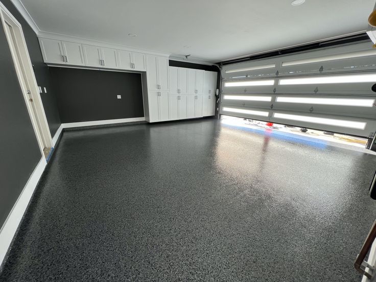 an empty garage with white cabinets and gray flooring is seen in this image from the inside