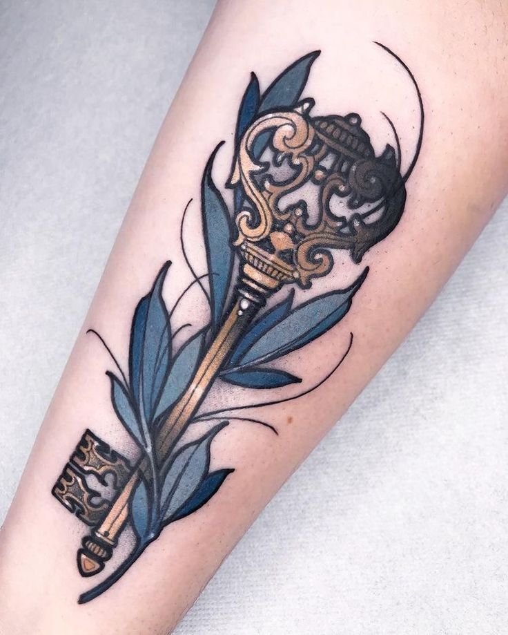 a tattoo with a key and feather on it