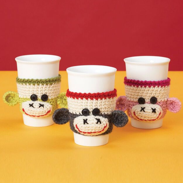 three coffee cups with knitted monkey faces on them