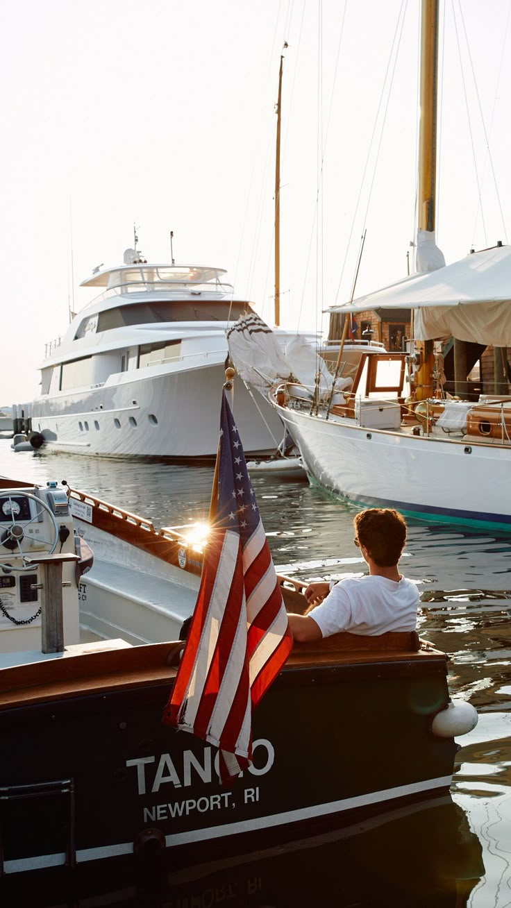 a man sitting in a boat with an american flag on the front and other boats behind him