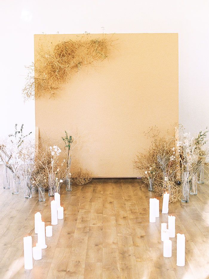 there are many vases and candles on the floor in front of a large wall