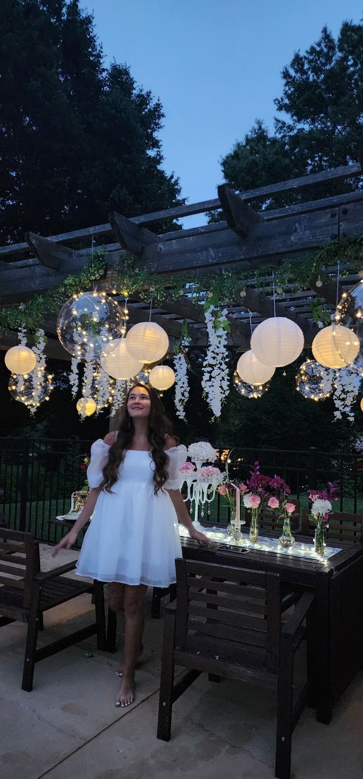 a woman standing in front of a table with lights hanging from it