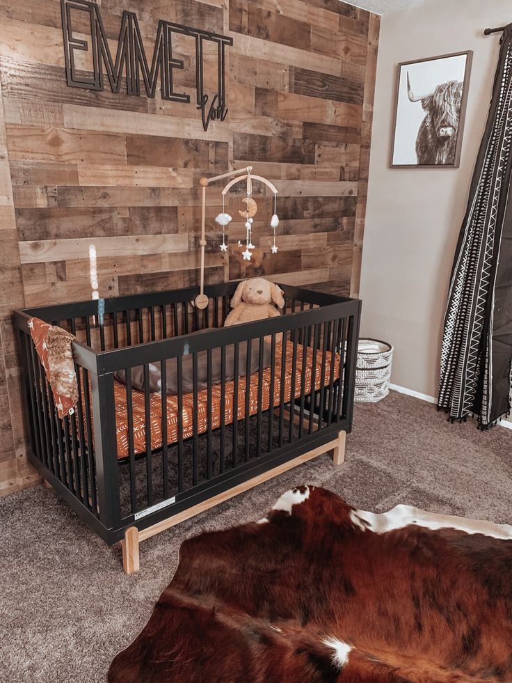 a baby's room with a wooden wall and cow skin rugs on the floor