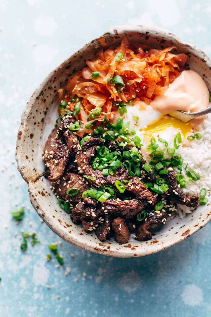 a bowl filled with rice, meat and veggies on top of a table