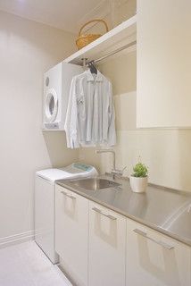 a laundry room with white cabinets and stainless steel sink